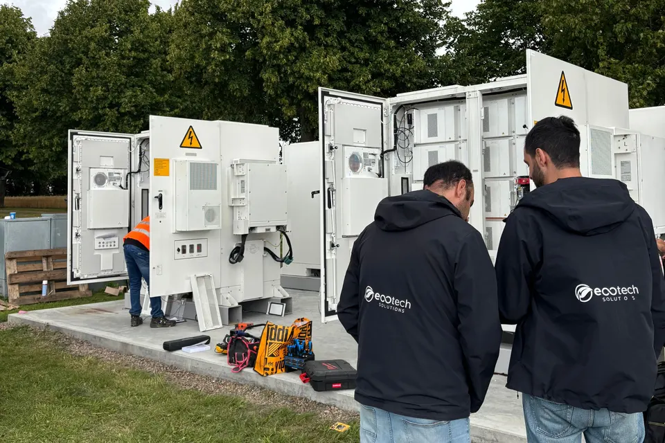 Två installatörer från EcoTech vid öppna batteriskåp utomhus